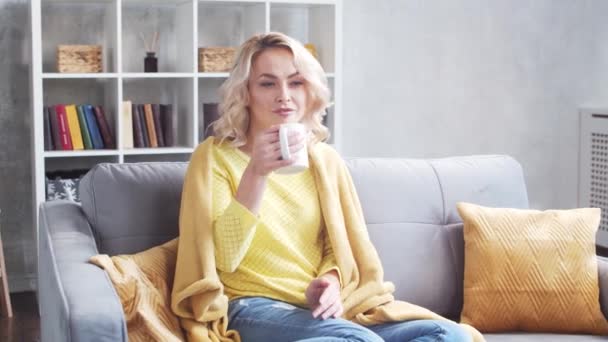 午前中に自宅で若く魅力的な女性 フリーランサーか学生がコーヒーを飲んでいる ロックダウンの概念 — ストック動画