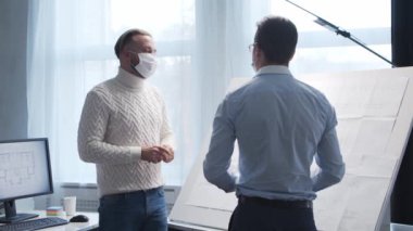 Mimar ve koruyucu maskeli meslektaşı. Erkekler tavan arasında çizim tahtası ve bilgisayar kullanarak çalışırlar. Modern ofiste genç inşaat mühendisinin işyeri. Gayrimenkul geliştirme kavramı.
