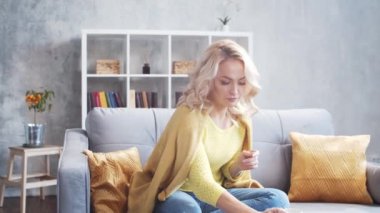 Genç ve çekici bir kadın evde dizüstü bilgisayar kullanarak çalışıyor. Freelancer ya da öğrenci kahve içiyor. Kilitleme kavramı.