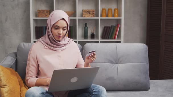 히잡에 매력적 이슬람 여성이 노트북 컴퓨터를 사용하여 인터넷에서 물건을 구입하고 — 비디오