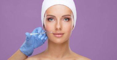 Genç bir kadının güzel yüzüne iğne yapan bir doktor. Estetik ameliyat, cilt gerdirme ve estetik tıp konsepti.