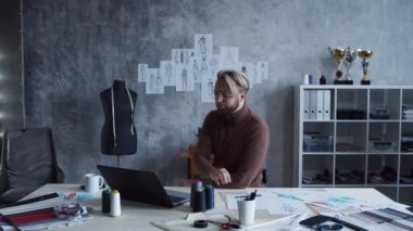 Genç ve yetenekli moda tasarımcılarının işyeri. Terzi şık çatı katında tek başına çalışıyor. Kıyafet çizimleri kullanıyor..