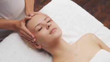 Genç, güzel ve sağlıklı bir kadın masaj salonunda. Geleneksel yüz masajı terapisi ve cilt bakımı.