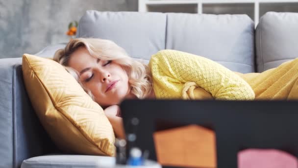 仕事に疲れたフリーランスの女の子は朝ソファの上で眠る 家で働いている間に若い女性は眠ってしまった ロックダウンとリモートジョブの概念 — ストック動画
