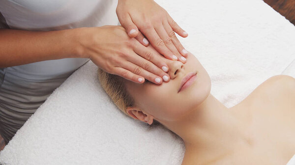 Молодая, красивая и здоровая женщина в массажном салоне. Традиционный массаж лица и уход за кожей.