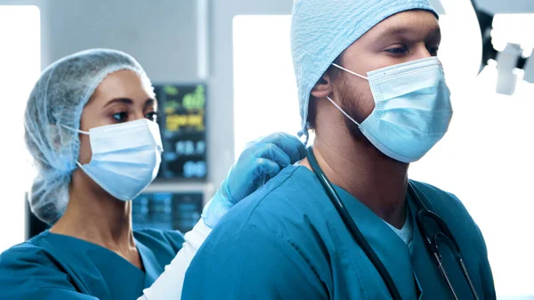 Professional medical doctors working in emergency medicine. Portrait of the surgeon and the nurse in protective masks performing surgical operation. Medical concept.