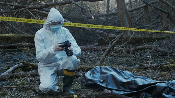 Detectives are collecting evidence in a crime scene. Forensic specialists are making expertise. Professional police investigation in a forest.