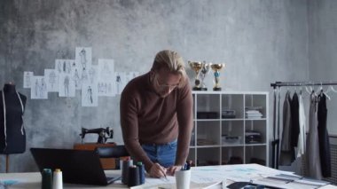 Genç ve yetenekli moda tasarımcılarının işyeri. Terzi şık çatı katında tek başına çalışıyor. Kıyafet çizimleri kullanıyor..