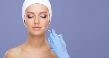 Genç bir kadının güzel yüzüne iğne yapan bir doktor. Estetik ameliyat, cilt gerdirme ve estetik tıp konsepti.