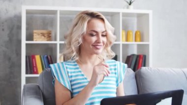 Genç ve çekici bir kadın evde dizüstü bilgisayar kullanarak çalışıyor. Kanepede serbest çalışan ya da öğrenci. Kilitleme kavramı.