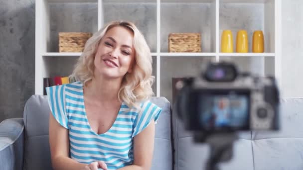 Νεαρή και ελκυστική γυναίκα καταγράφει βίντεο blog με κάμερα. Κορίτσι κάθεται στο σπίτι και vlogging. — Αρχείο Βίντεο