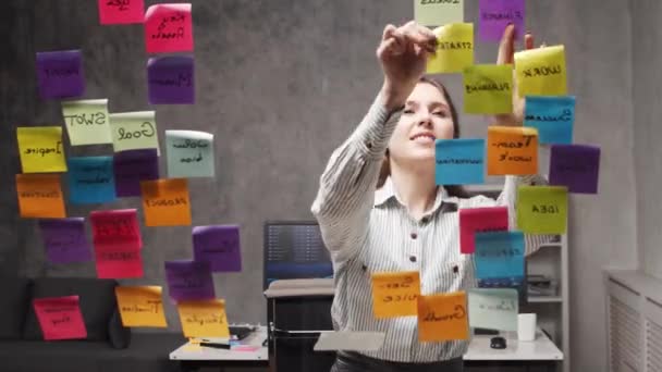 Timelapse de la joven mujer de negocios está haciendo una lluvia de ideas usando pegatinas en el vidrio. El oficinista está pensando en estrategia, plan de negocios y metas. Concepto de inicio. — Vídeos de Stock