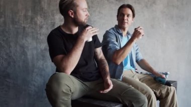 İki arkadaş iç yenileme molasında dinleniyor ve konuşuyorlar. Erkek işçiler iskelede oturur ve kahve içerler..