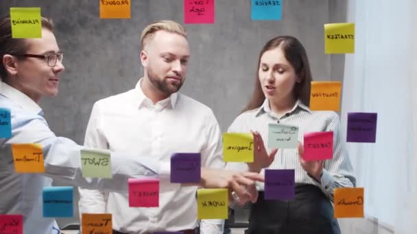 Tim bisnis orang-orang melakukan brainstorming pada pertemuan menggunakan stiker di kaca. Pekerja kantor sedang membahas strategi, rencana bisnis dan tujuan. Konsep startup. — Stok Video