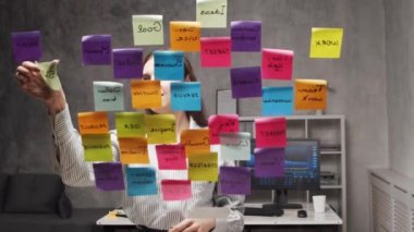 Genç iş kadını camdaki çıkartmaları kullanarak beyin fırtınası yapıyor. Ofis çalışanı strateji, iş planı ve hedefleri düşünüyor. Başlangıç konsepti.