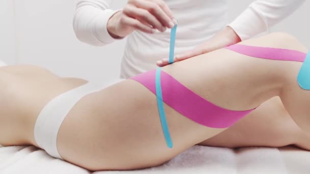 Therapeut brengt kinesio tape aan op vrouwelijk lichaam. Begrippen fysiotherapie en kinesiologie. — Stockvideo
