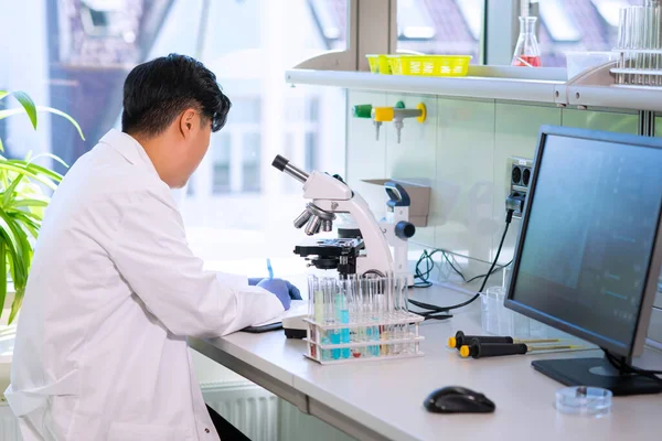 Azjatycki lekarz pracujący w laboratorium badawczym. Asystent naukowy robi eksperymenty farmaceutyczne. Chemia, medycyna, biochemia, biotechnologia i opieka zdrowotna. — Zdjęcie stockowe