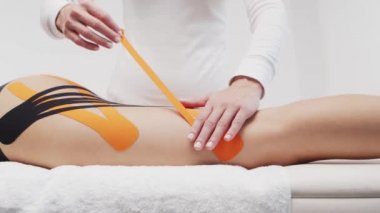 Terapist kadın vücuduna kinesio bandı uyguluyor. Fizyoterapi, kineziyoloji ve iyileşme tedavisi.