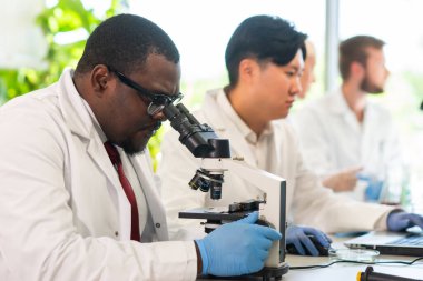 Laboratuvarda çalışan bir bilim adamı. Doktorlar tıbbi araştırma yapıyor. Biyoteknoloji, kimya, bilim, deneyler ve sağlık konsepti. Gün ışığı ve pencere arkaplanı.