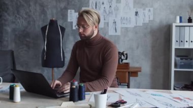 Genç ve yetenekli moda tasarımcılarının işyeri. Terzi şık bir çatı katında kıyafet çizimleri kullanarak çalışıyor..