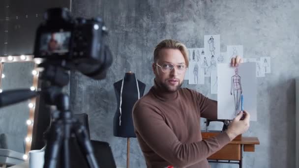 Młody vlogger mody nagrywa wideo vlog o projektowaniu ubrań. Strumień utalentowanych stylistów z jego miejsca pracy w nowoczesnym poddaszu. — Wideo stockowe