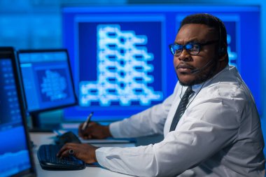 Afro-Amerikalı borsacı, çalışma istasyonu ve analiz teknolojisi kullanarak ofiste çalışıyor. Profesyonel tüccarların işyeri. Küresel finans piyasaları, iş dünyası, döviz kurları ve bankacılık kavramları.