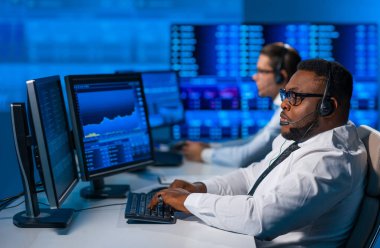 Komisyonculardan oluşan bir ekip, çalışma istasyonu ve analiz teknolojisini kullanarak ofiste çalışıyor. Profesyonel tüccarların işyeri. Küresel finans piyasaları, iş dünyası, döviz kurları ve bankacılık kavramları.