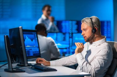 Komisyonculardan oluşan bir ekip, çalışma istasyonu ve analiz teknolojisini kullanarak ofiste çalışıyor. Profesyonel tüccarların işyeri. Küresel finans piyasaları, iş dünyası, döviz kurları ve bankacılık kavramları.