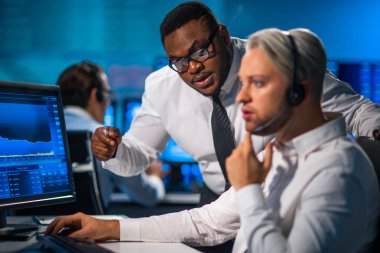 Komisyonculardan oluşan bir ekip, çalışma istasyonu ve analiz teknolojisini kullanarak ofiste çalışıyor. Profesyonel tüccarların işyeri. Küresel finans piyasaları, iş dünyası, döviz kurları ve bankacılık kavramları.