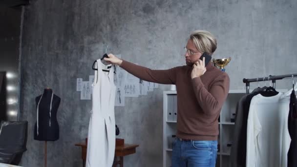 Arbeitsplatz junger und talentierter Modedesigner. Schneider arbeitet in stilvollem Loft anhand von Kleidungsskizzen. — Stockvideo