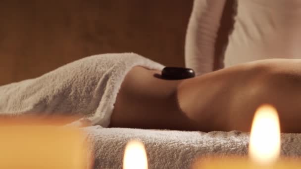 Молода і красива жінка отримує гарячу кам'яну масажну терапію в спа-салоні. Здоровий спосіб життя та концепція догляду за тілом . — стокове відео