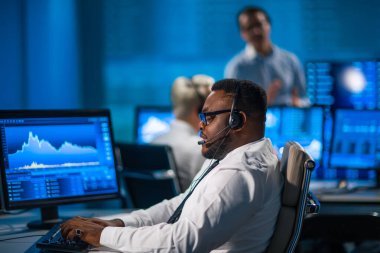 Komisyonculardan oluşan bir ekip, çalışma istasyonu ve analiz teknolojisini kullanarak ofiste çalışıyor. Profesyonel tüccarların işyeri. Küresel finans piyasaları, iş dünyası, döviz kurları ve bankacılık kavramları.