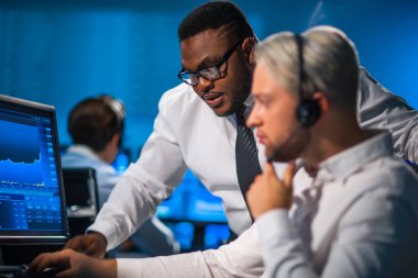 Komisyonculardan oluşan bir ekip, çalışma istasyonu ve analiz teknolojisini kullanarak ofiste çalışıyor. Profesyonel tüccarların işyeri. Küresel finans piyasaları, iş dünyası, döviz kurları ve bankacılık kavramları.