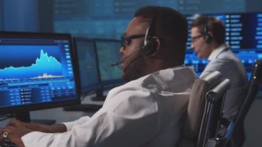 Ofiste çalışan çeşitli simsarlar çalışma istasyonu ve analiz teknolojisi kullanıyor. Profesyonel tüccarların işyeri. Küresel finans piyasaları, iş dünyası, döviz kurları ve bankacılık kavramları.