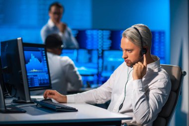 Komisyonculardan oluşan bir ekip, çalışma istasyonu ve analiz teknolojisini kullanarak ofiste çalışıyor. Profesyonel tüccarların işyeri. Küresel finans piyasaları, iş dünyası, döviz kurları ve bankacılık kavramları.