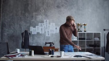 Genç ve yetenekli moda tasarımcılarının işyeri. Terzi şık bir çatı katında kıyafet çizimleri kullanarak çalışıyor..