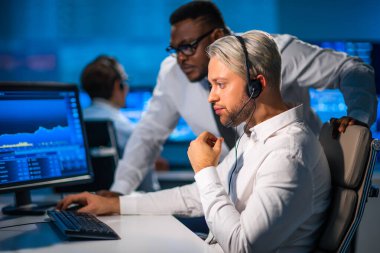 Komisyonculardan oluşan bir ekip, çalışma istasyonu ve analiz teknolojisini kullanarak ofiste çalışıyor. Profesyonel tüccarların işyeri. Küresel finans piyasaları, iş dünyası, döviz kurları ve bankacılık kavramları.