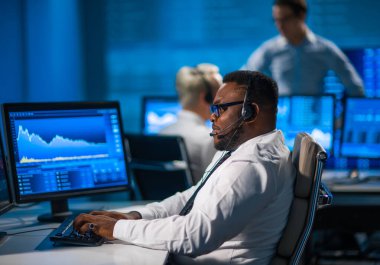 Komisyonculardan oluşan bir ekip, çalışma istasyonu ve analiz teknolojisini kullanarak ofiste çalışıyor. Profesyonel tüccarların işyeri. Küresel finans piyasaları, iş dünyası, döviz kurları ve bankacılık kavramları.