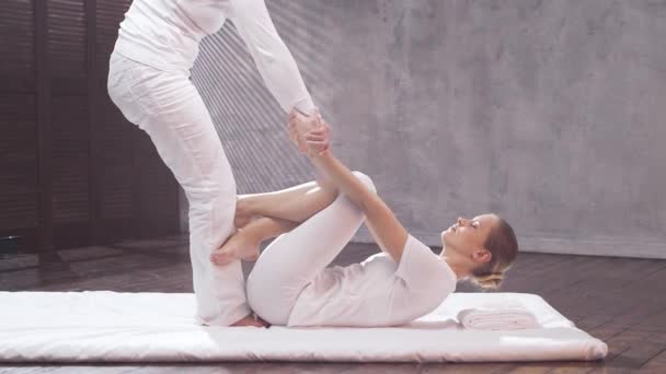 Jonge vrouw krijgt Thaise massage behandeling door therapeut. Traditionele Aziatische stretching therapie. — Stockvideo