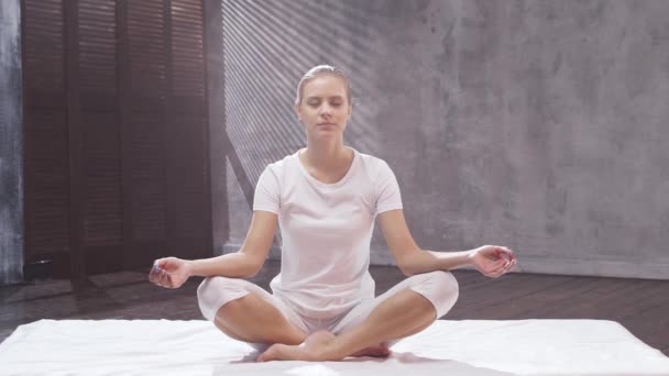 Jonge en fitte vrouw oefent yoga indoor in de klas. Uitrekken oefening in het daglicht. Sport, fitness, gezondheidszorg en lifestyle concepten. — Stockvideo