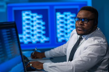 Afro-Amerikalı borsacı, çalışma istasyonu ve analiz teknolojisi kullanarak ofiste çalışıyor. Profesyonel tüccarların işyeri. Küresel finans piyasaları, iş dünyası, döviz kurları ve bankacılık kavramları.