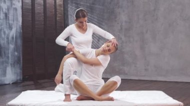 Genç bir kadın terapist tarafından Tayland masajı görüyor. Geleneksel Asya esneme terapisi.