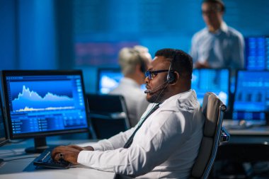 Komisyonculardan oluşan bir ekip, çalışma istasyonu ve analiz teknolojisini kullanarak ofiste çalışıyor. Profesyonel tüccarların işyeri. Küresel finans piyasaları, iş dünyası, döviz kurları ve bankacılık kavramları.