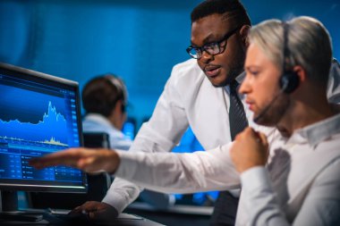 Komisyonculardan oluşan bir ekip, çalışma istasyonu ve analiz teknolojisini kullanarak ofiste çalışıyor. Profesyonel tüccarların işyeri. Küresel finans piyasaları, iş dünyası, döviz kurları ve bankacılık kavramları.