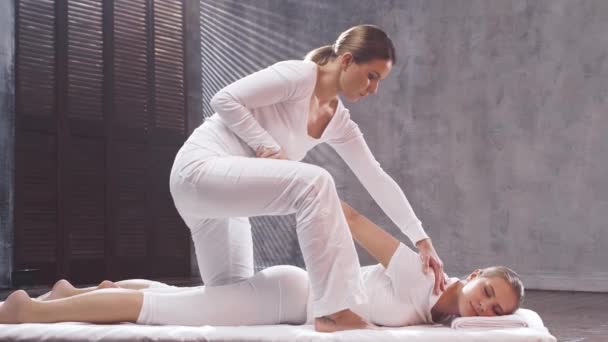Mujer joven está recibiendo tratamiento de masaje tailandés por terapeuta. Terapia tradicional de estiramiento asiático. — Vídeos de Stock