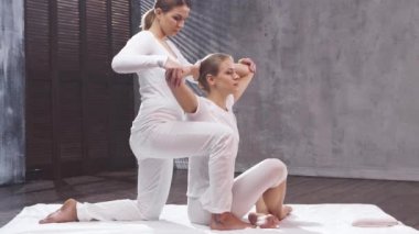 Genç bir kadın terapist tarafından Tayland masajı görüyor. Geleneksel Asya esneme terapisi.