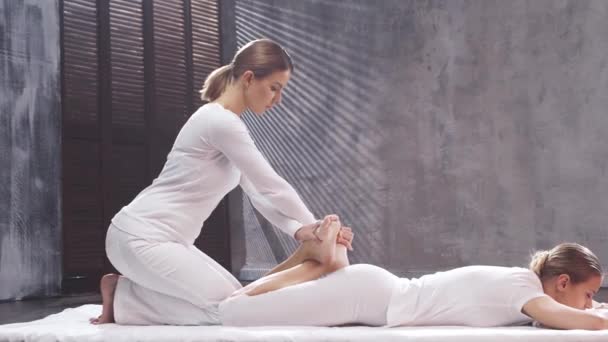 Ung kvinna får thaimassagebehandling av terapeut. Traditionell asiatisk stretchterapi. — Stockvideo