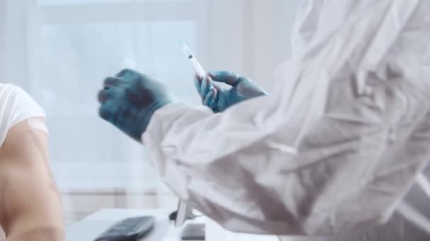 Afroamerický lékař vyrobí koronavirovou vakcínu pomocí injekční stříkačky a podkožní jehly. Zdravotník a pacient v nemocniční kanceláři. Koncepce vakcinace a bezpečnosti. — Stock video
