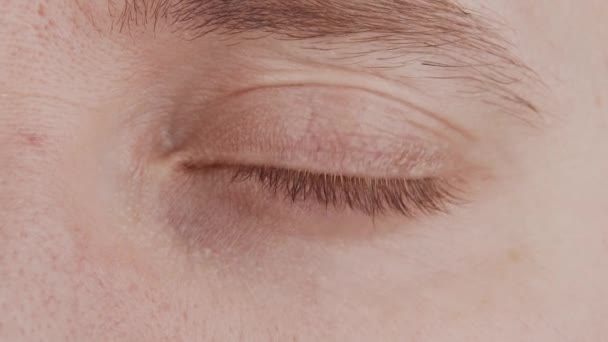 Detailní záběr mužského modrého oka. Muž se dívá do kamery zblízka. Makro duhovky, zornice a obočí. Poruchy zraku, oftalmologie a optometrie. — Stock video