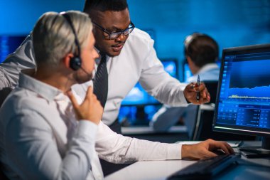 Komisyonculardan oluşan bir ekip, çalışma istasyonu ve analiz teknolojisini kullanarak ofiste çalışıyor. Profesyonel tüccarların işyeri. Küresel finans piyasaları, iş dünyası, döviz kurları ve bankacılık kavramları.